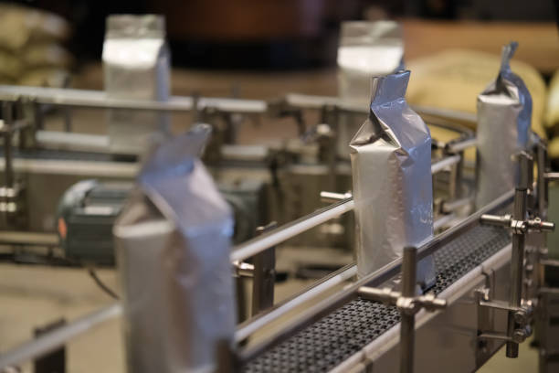 roasted coffee beans in package on conveyor belt in factory. 