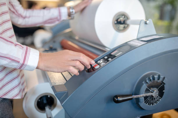 At workshop. Female hands, pushing buttons, adjusting paper roll machine